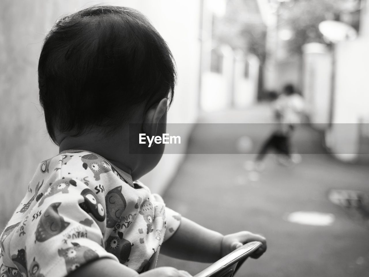 Close-up of toddler on chair looking at street in town