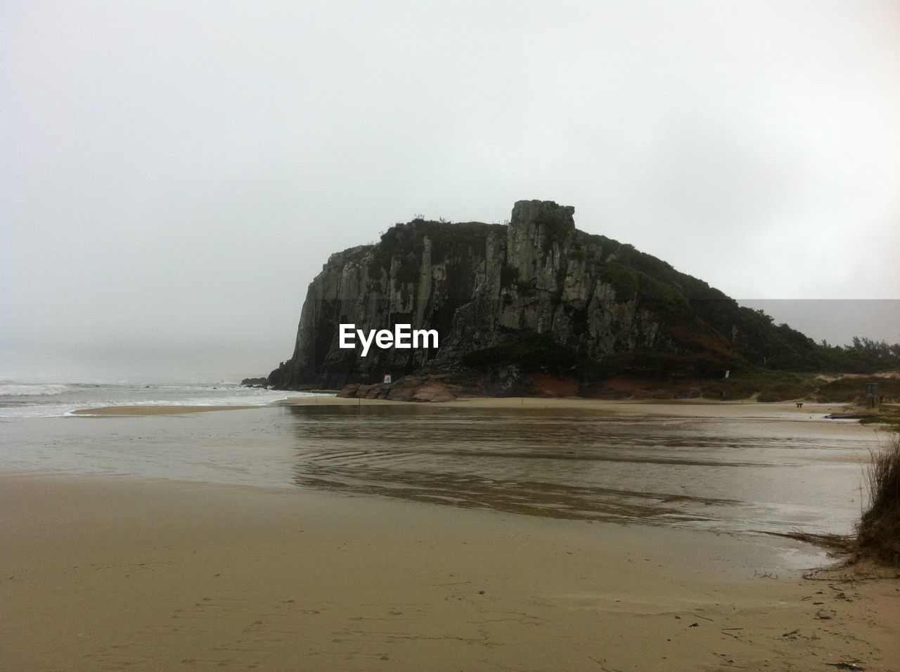 Scenic view of wet shore and mountain against sky