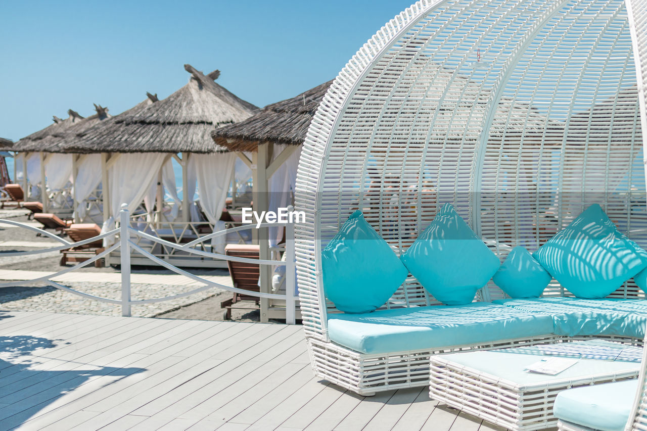 LOUNGE CHAIRS BY SWIMMING POOL AGAINST SKY