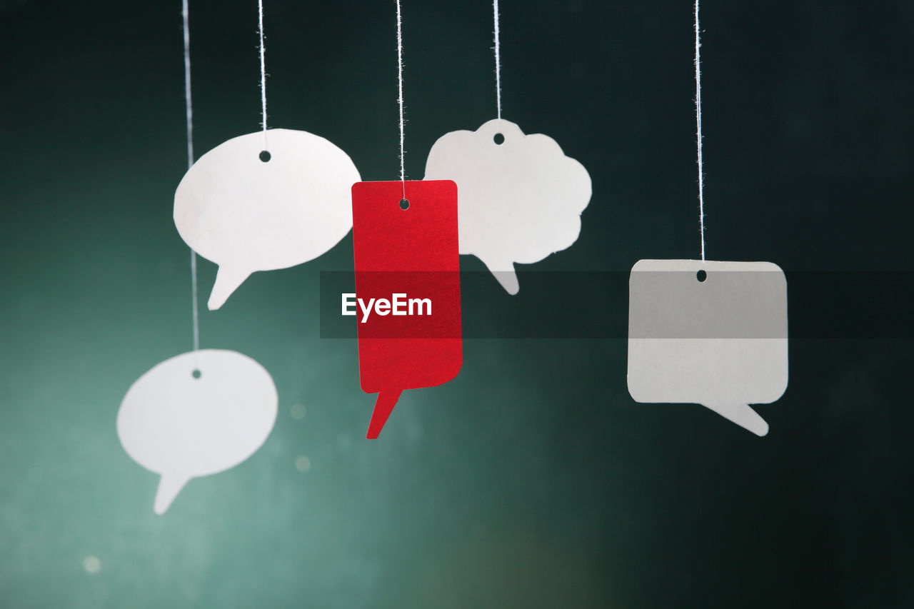 Close-up of speech bubbles hanging against wall