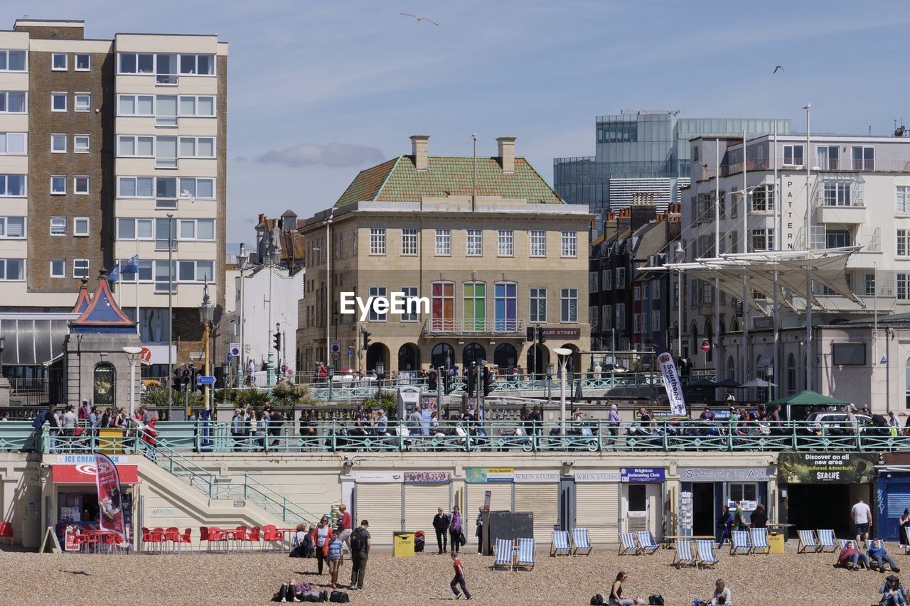 PEOPLE AT BEACH AGAINST BUILDINGS