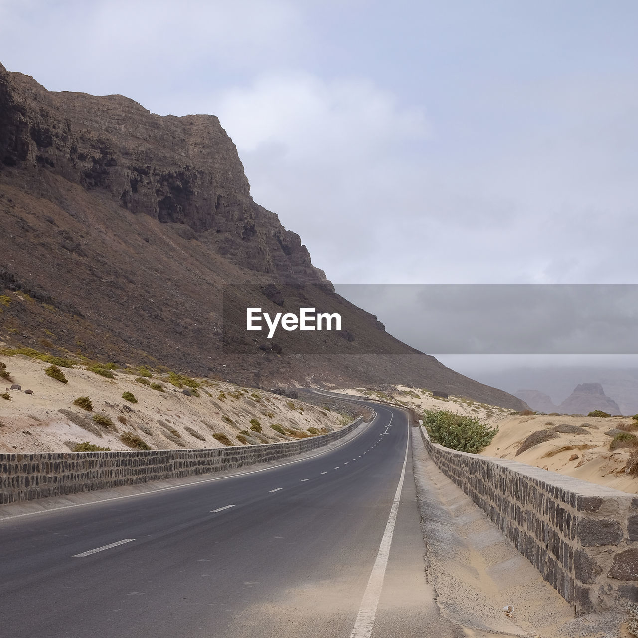 Empty road by mountain against sky