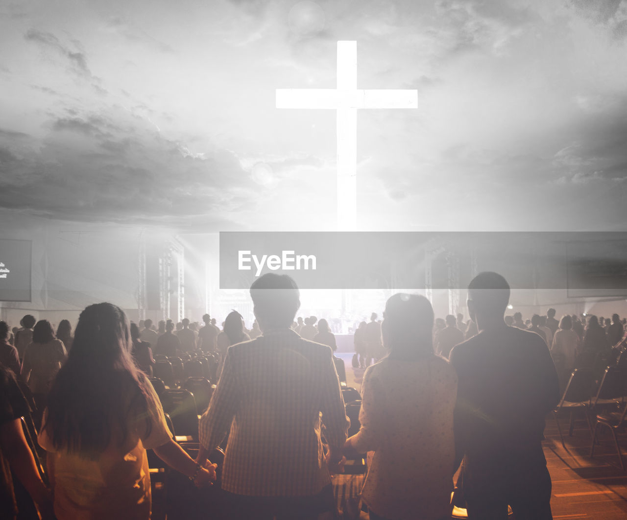 Rear view of people praying against cloudy sky at night