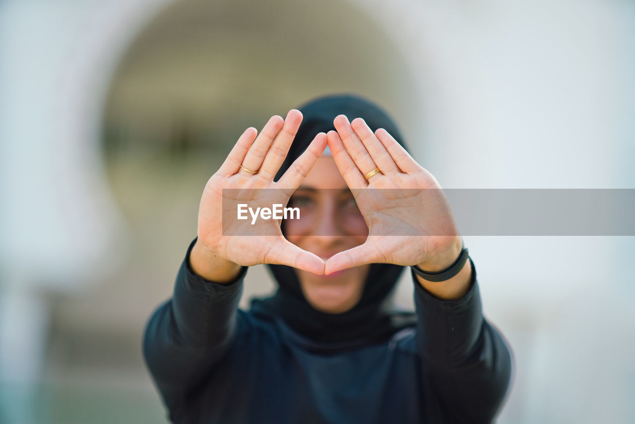 Portrait of young woman in hijab gesturing while outdoors