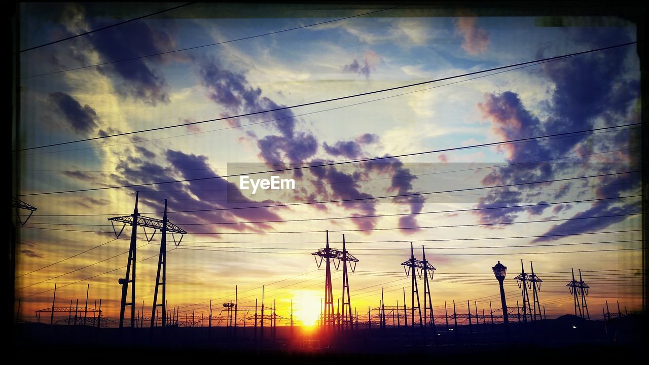 LOW ANGLE VIEW OF ELECTRICITY PYLON AGAINST DRAMATIC SKY