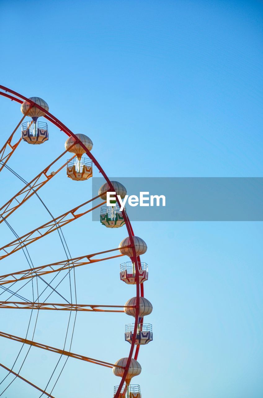 Low angle view of ferris wheel against clear blue sky