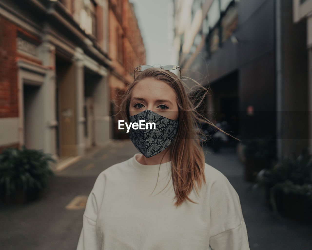 Portrait of beautiful woman wearing mask standing on street in city