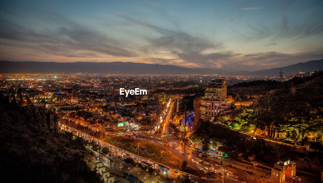 High angle view of illuminated cityscape against sky at sunset