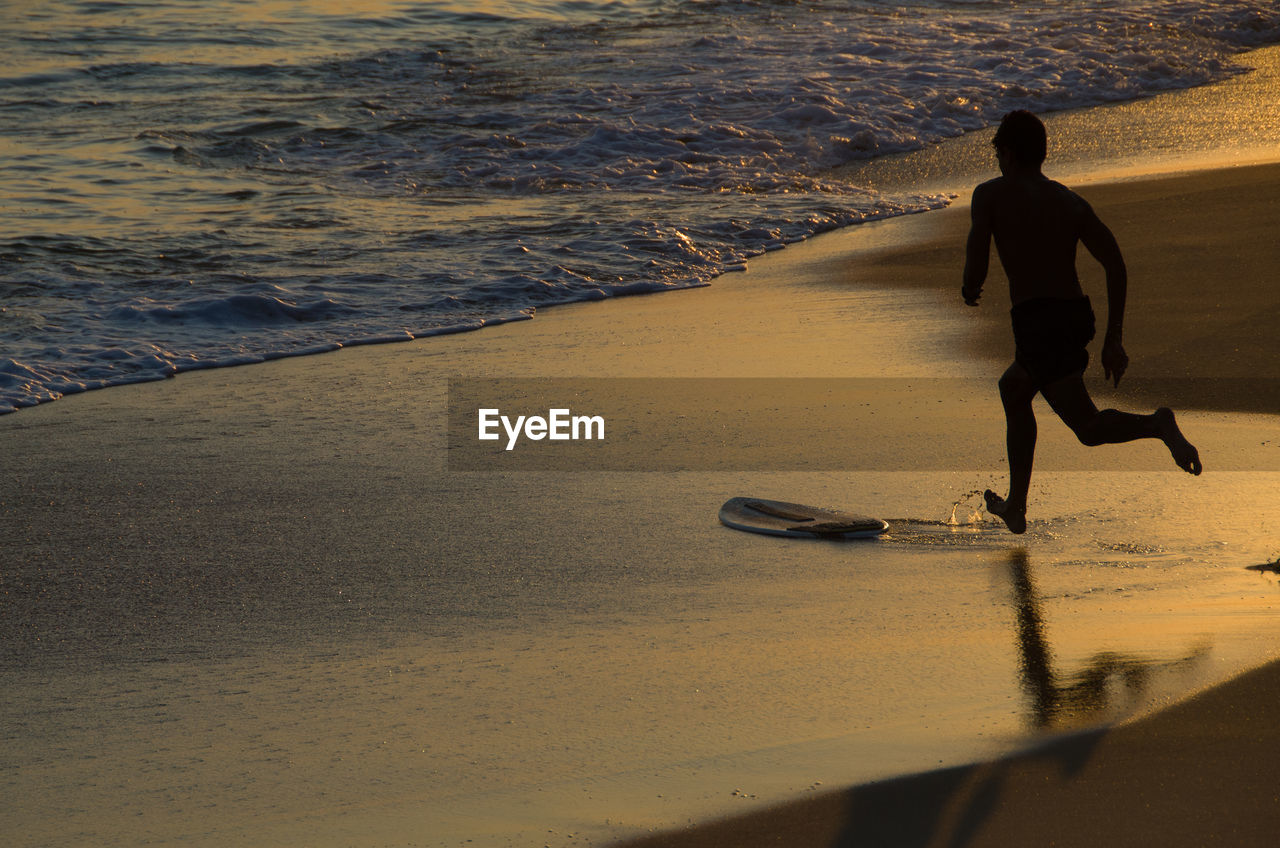 Full length of man running on beach during sunset