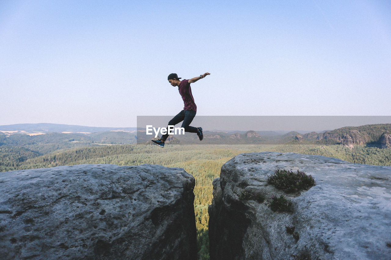 FULL LENGTH OF YOUNG MAN JUMPING IN MID-AIR