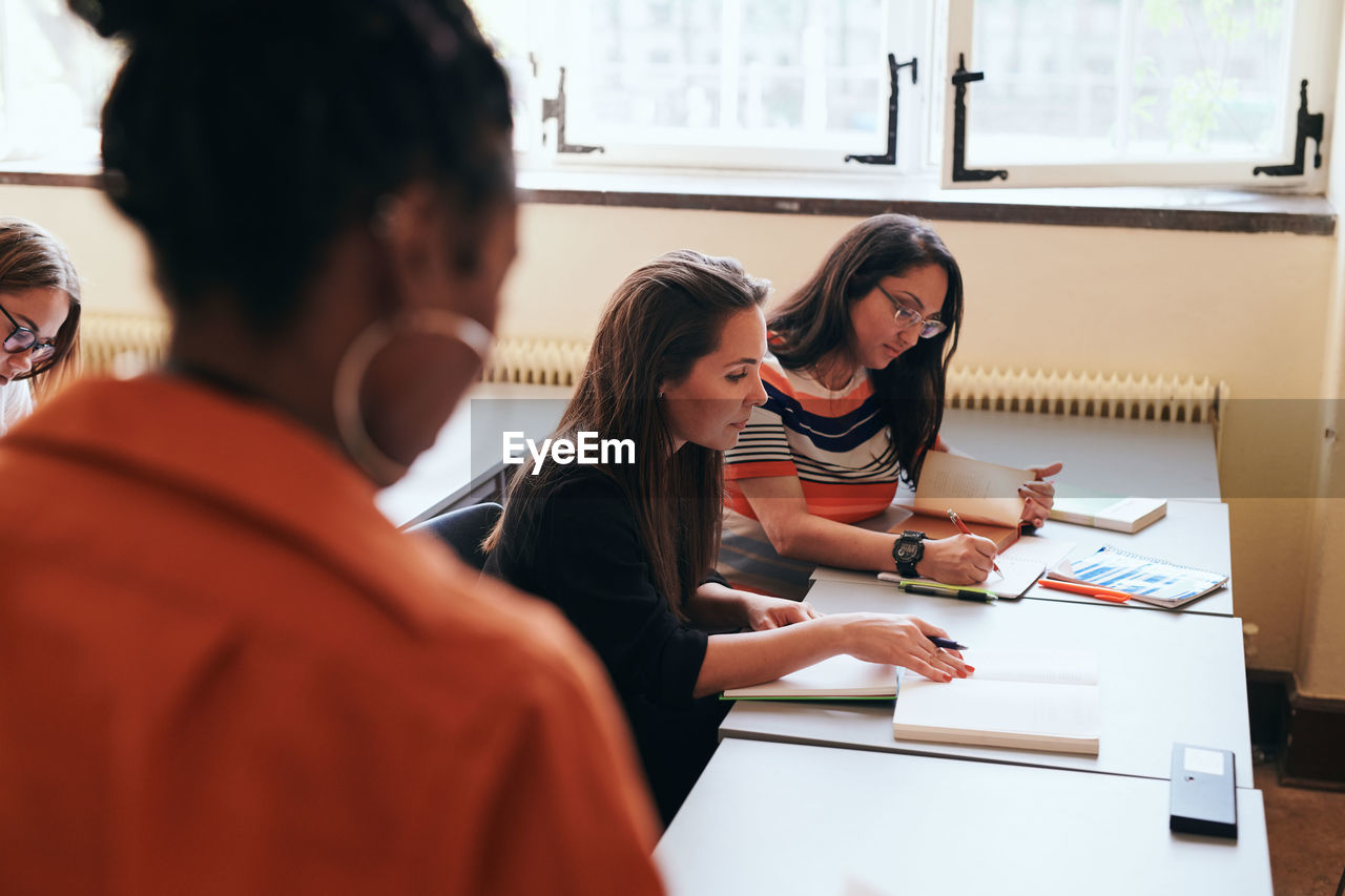 Female students writing in books in language school