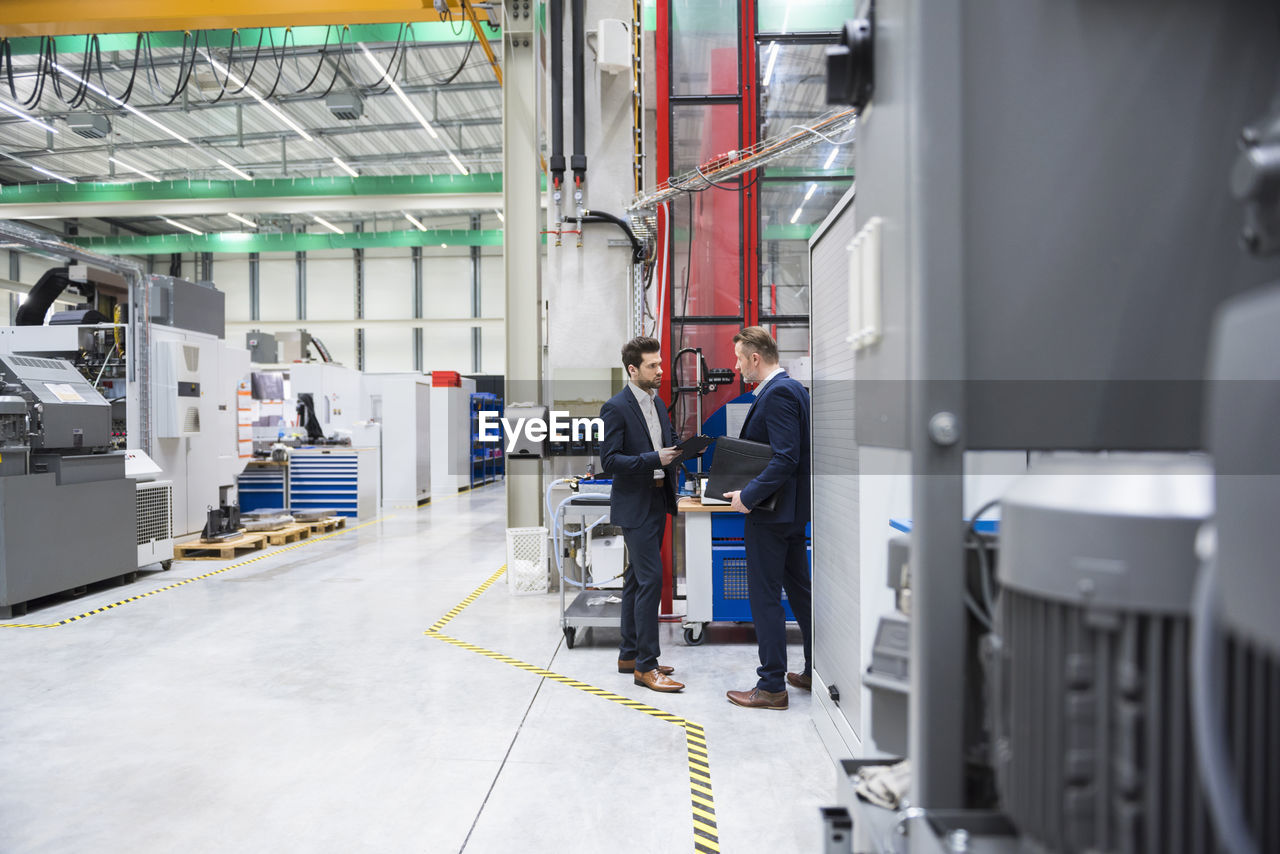 Two businessmen in factory shop floor