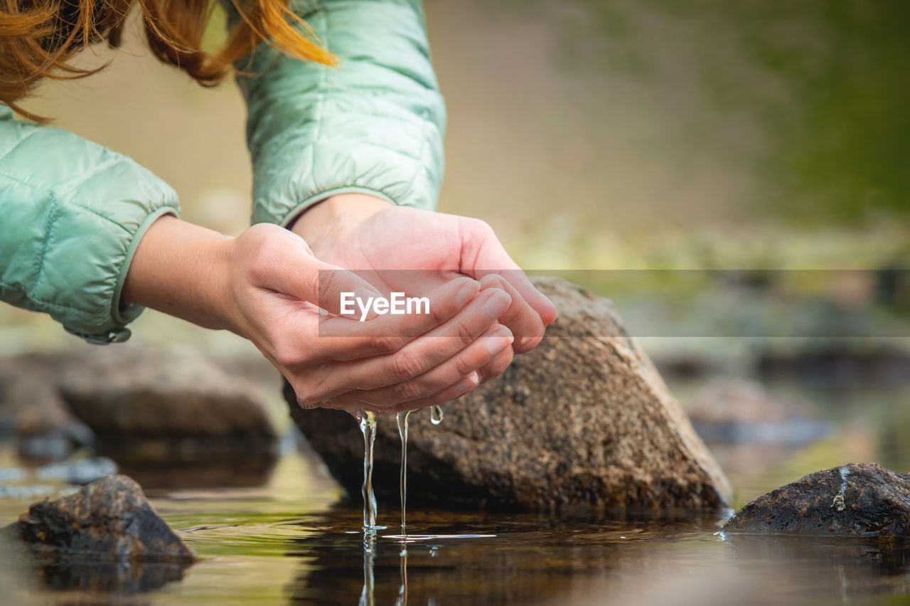 Hands and water. close-up of a woman taking water from a mountain lake in her hands