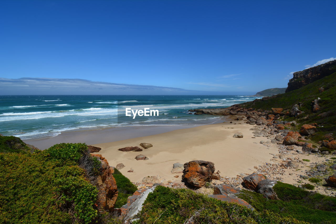 Scenic view of beach against clear blue sky