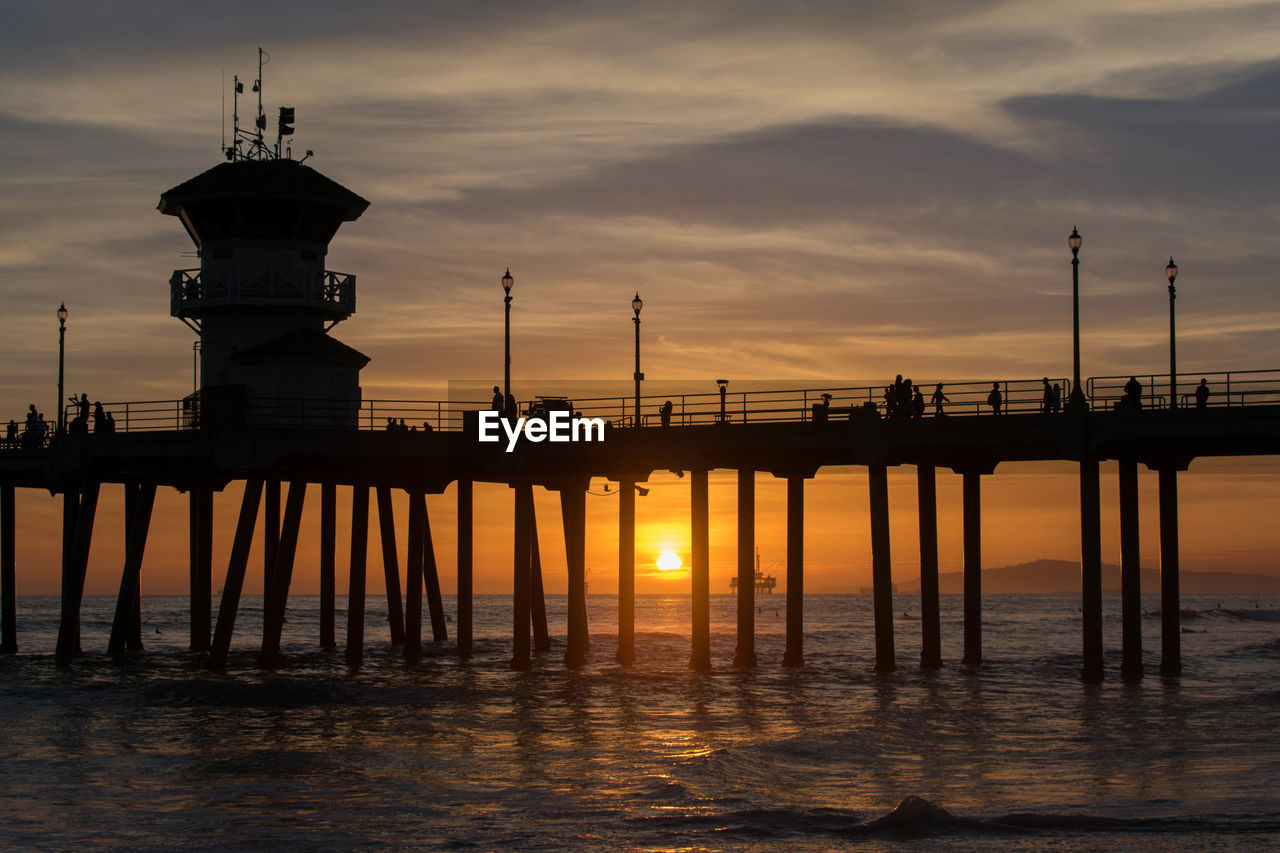 Silhouette pier over sea against sky during sunset