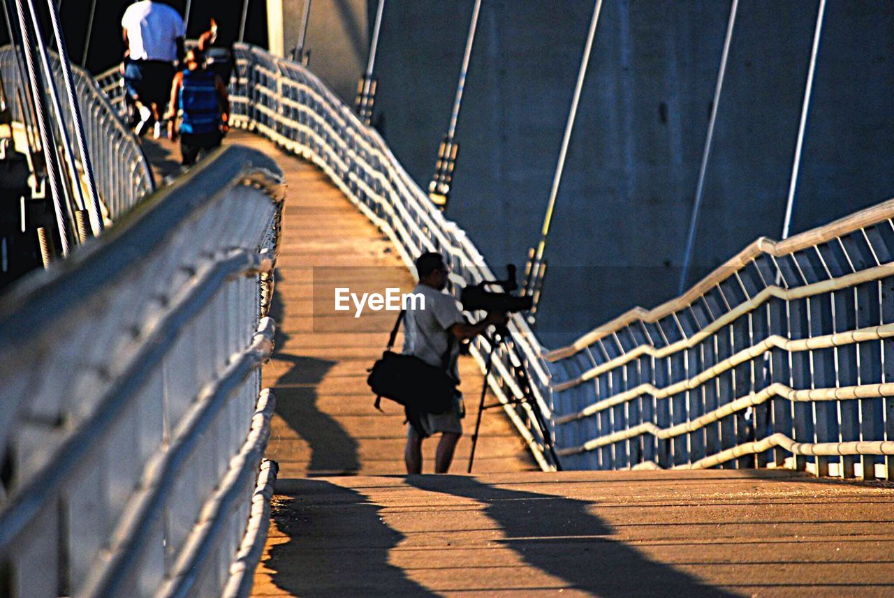 Photographer photographing through camera while standing on bridge