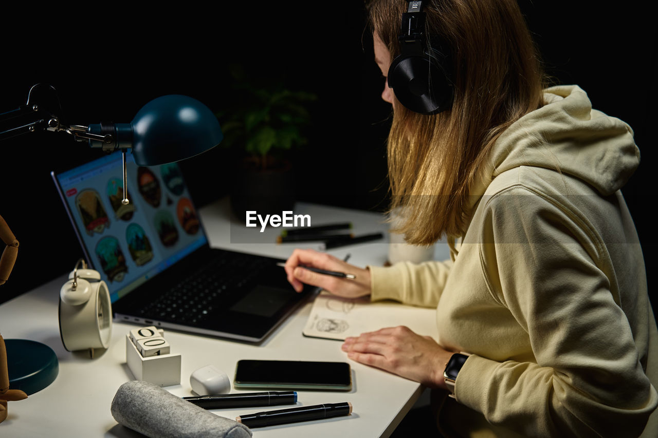 Woman working from home workplace at night, using laptop