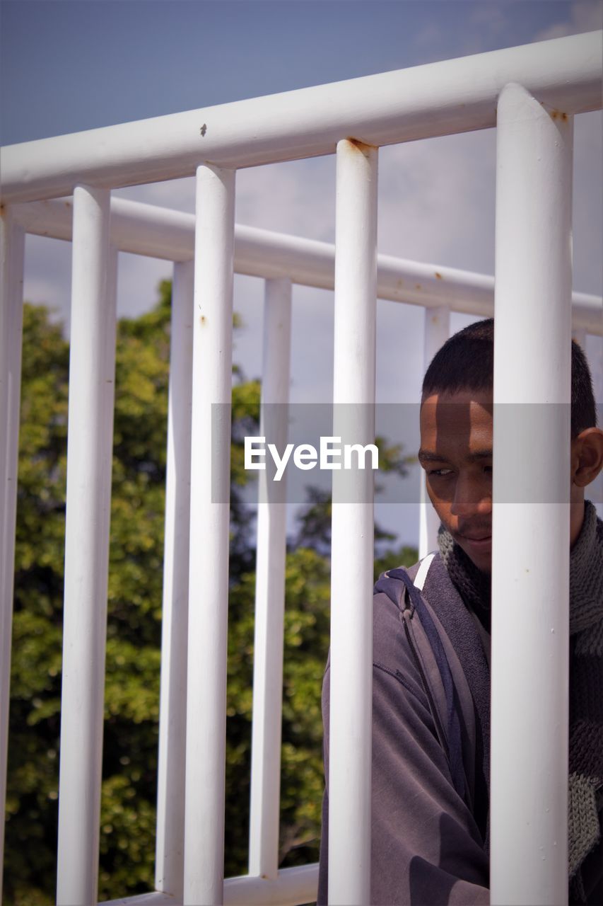 PORTRAIT OF MAN STANDING AGAINST RAILING