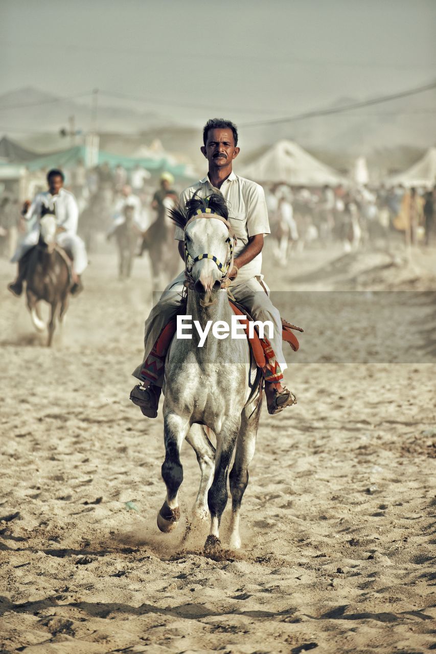 Full length of man riding horse on sand