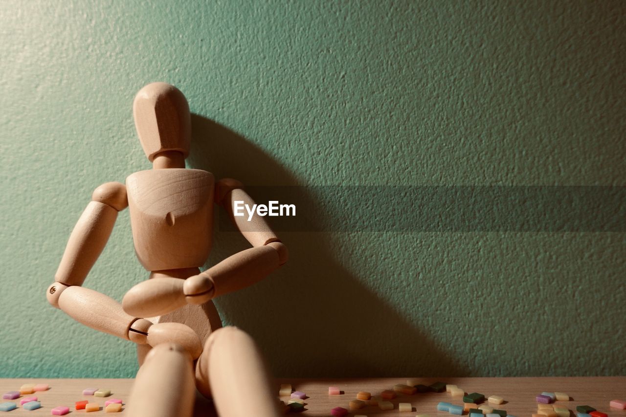 Close-up of wooden figurine on table against wall