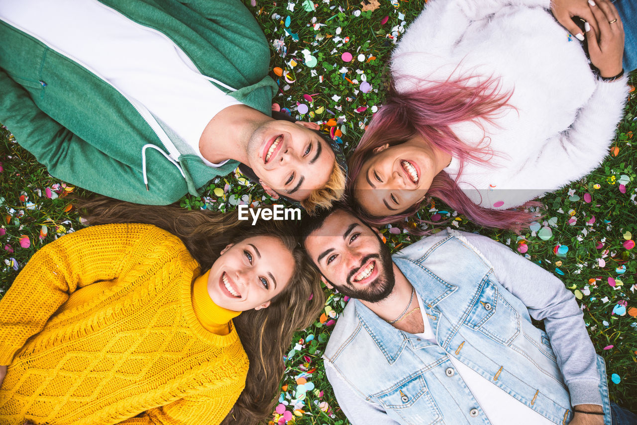 High angle view of cheerful friends lying on grassy land