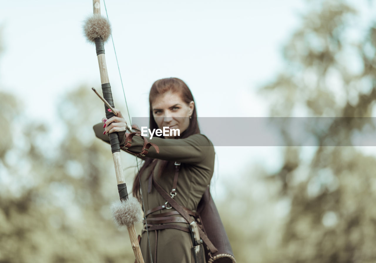 Archer holding bow and arrow while standing outdoors