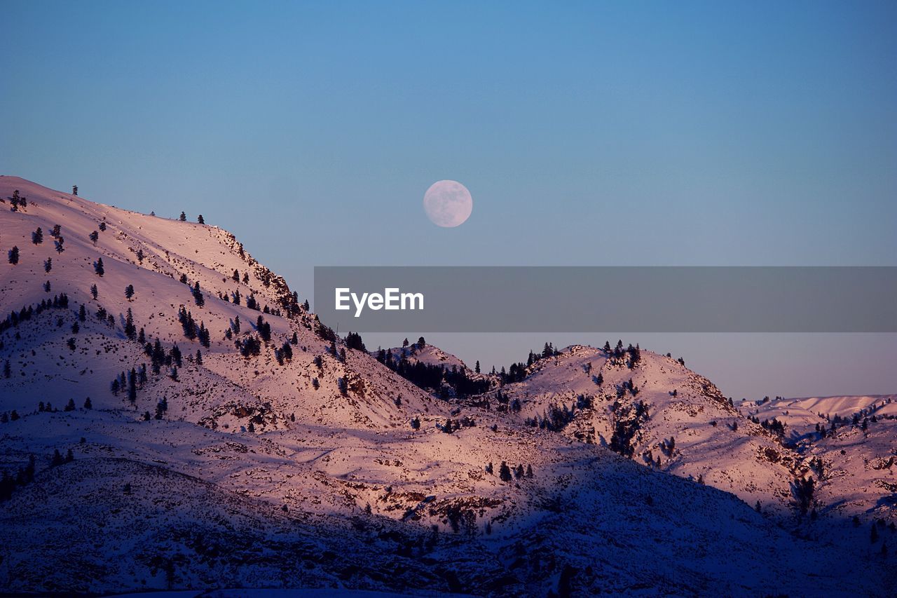 Scenic view of mountains against blue sky lit from a full moon