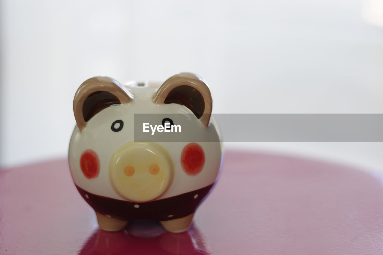 Close-up of piggy bank on table against white background