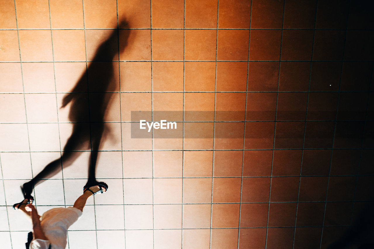 Low section of woman walking with shadow on footpath