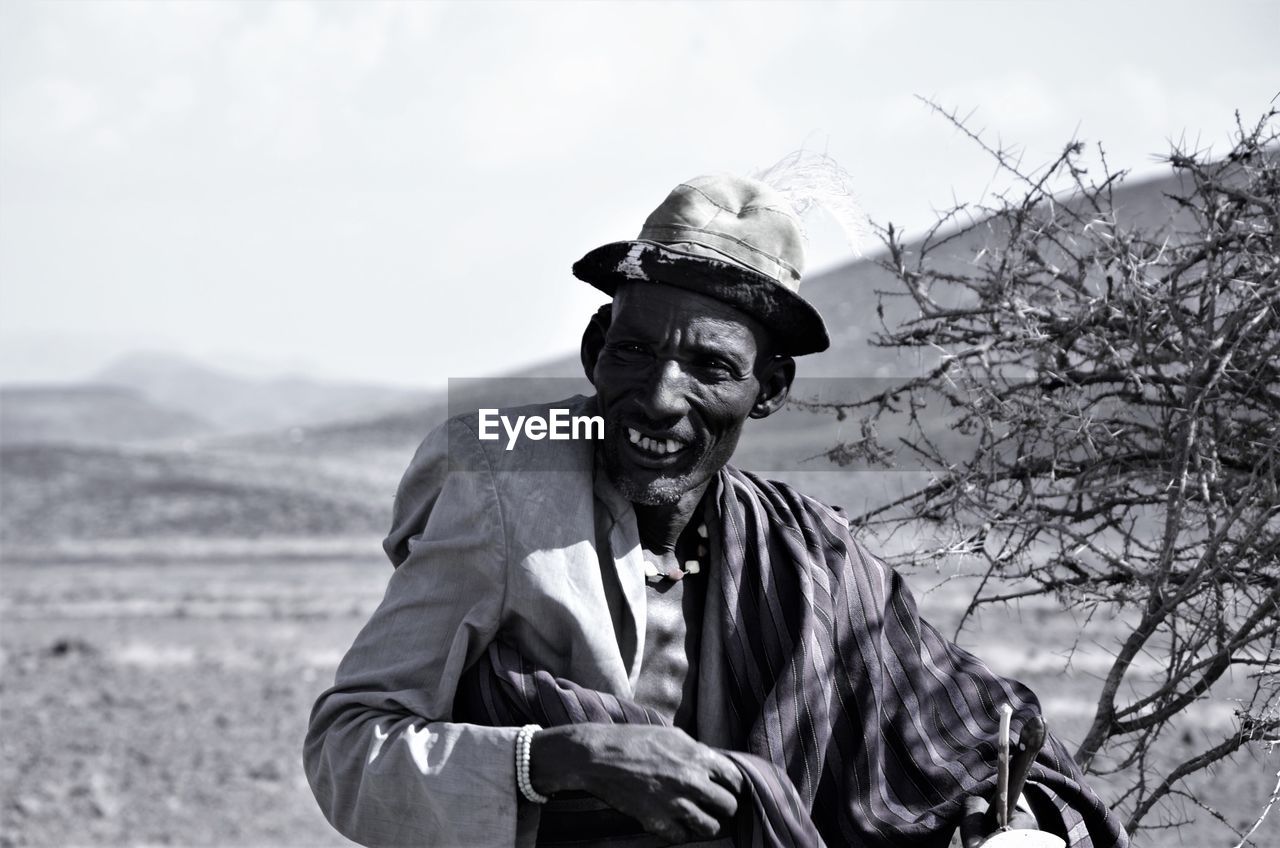 Smiling man standing on field against clear sky