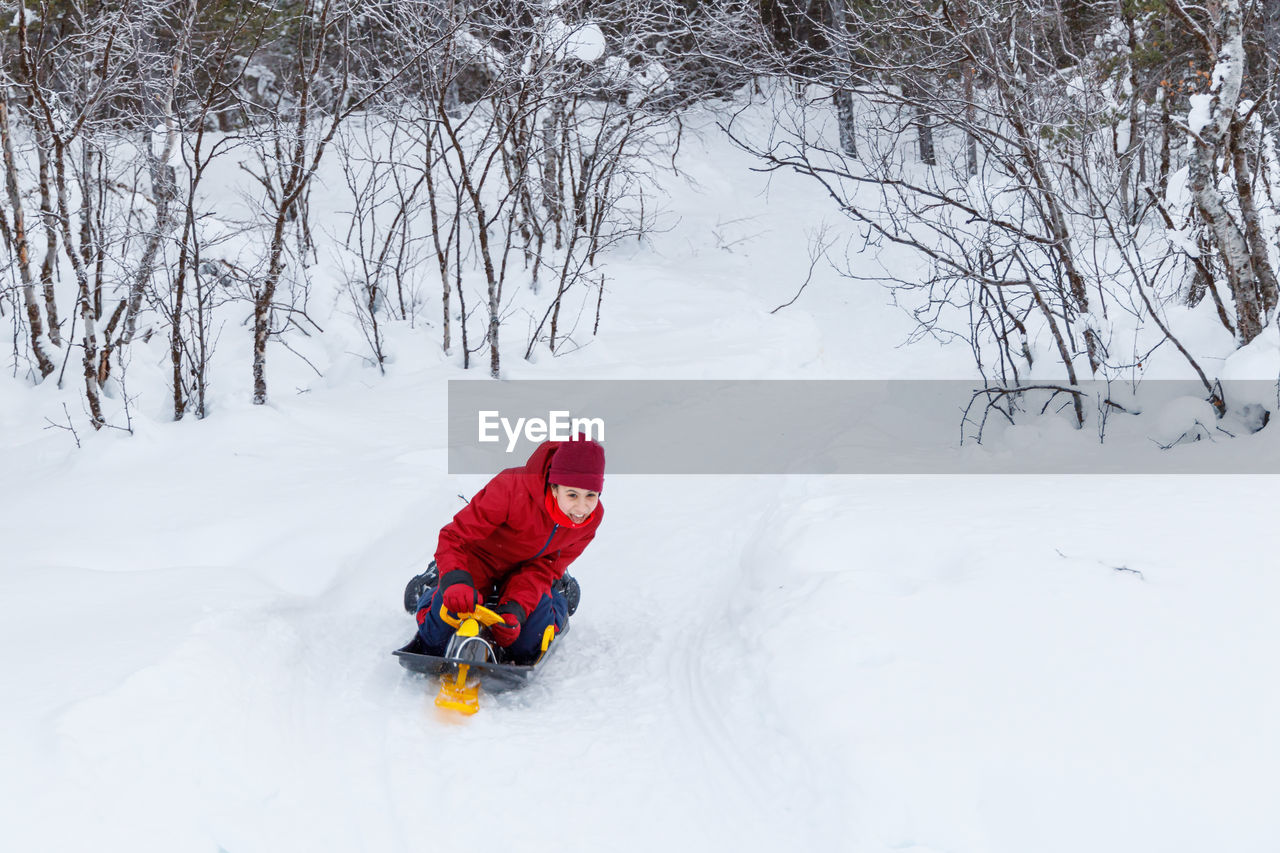 Girl sledding on a snow track, family vacation