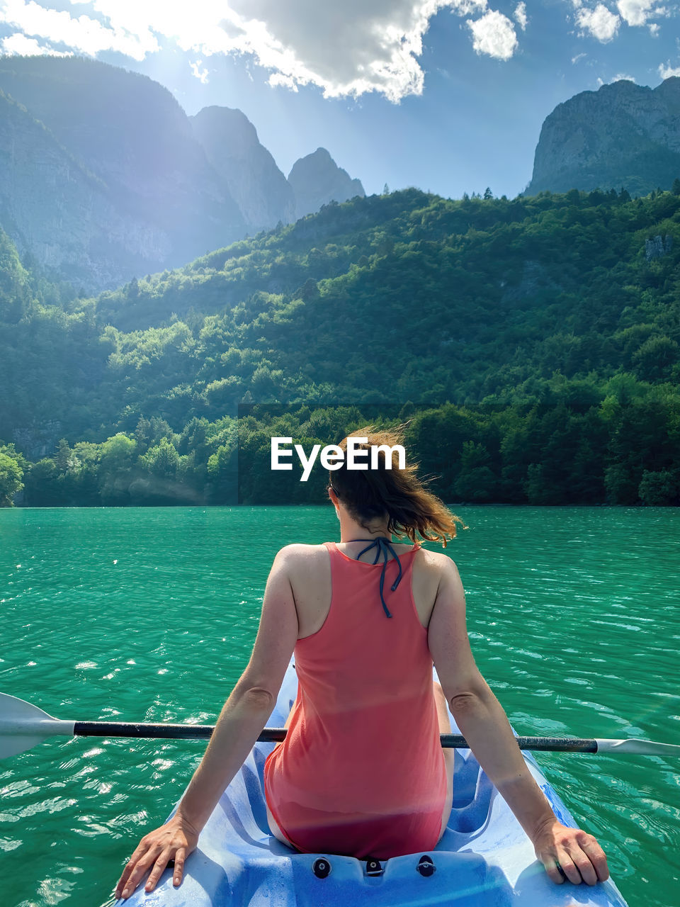 Young woman paddling on kayak at molveno lake, italy.