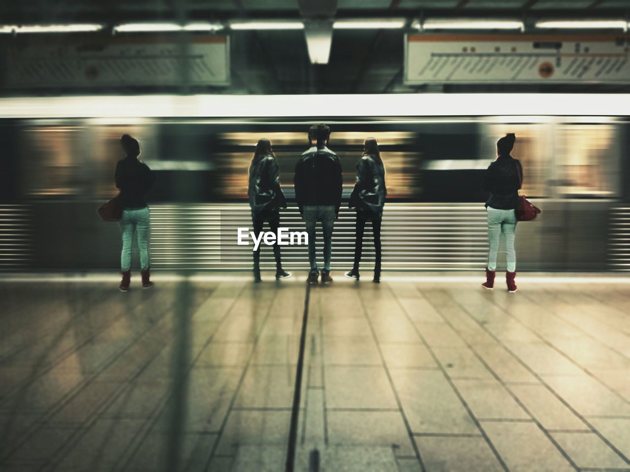 Reflection of people standing on railroad station platform by moving train on wall