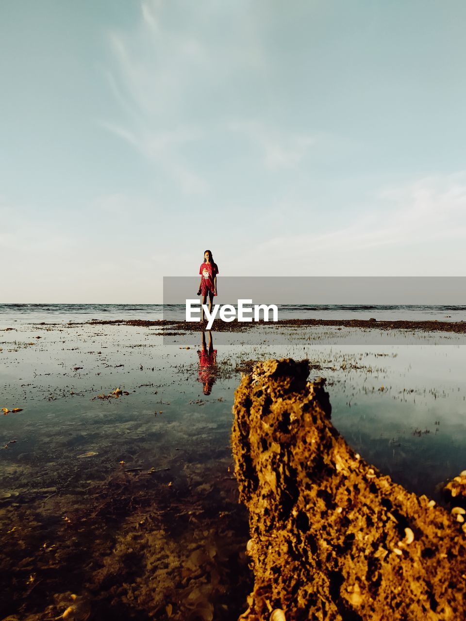 Rear view of woman walking on beach against sky