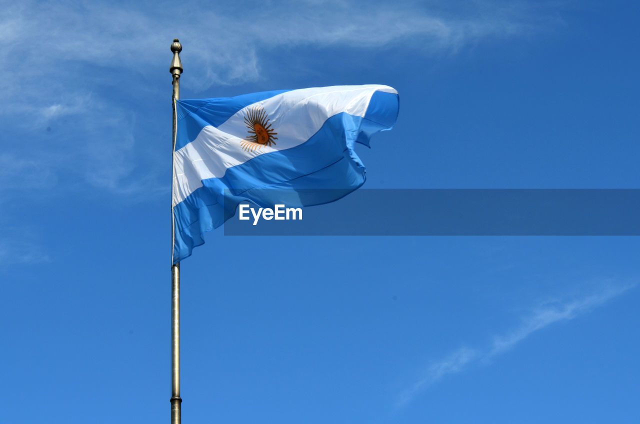 Low angle view of argentinian flag against blue sky