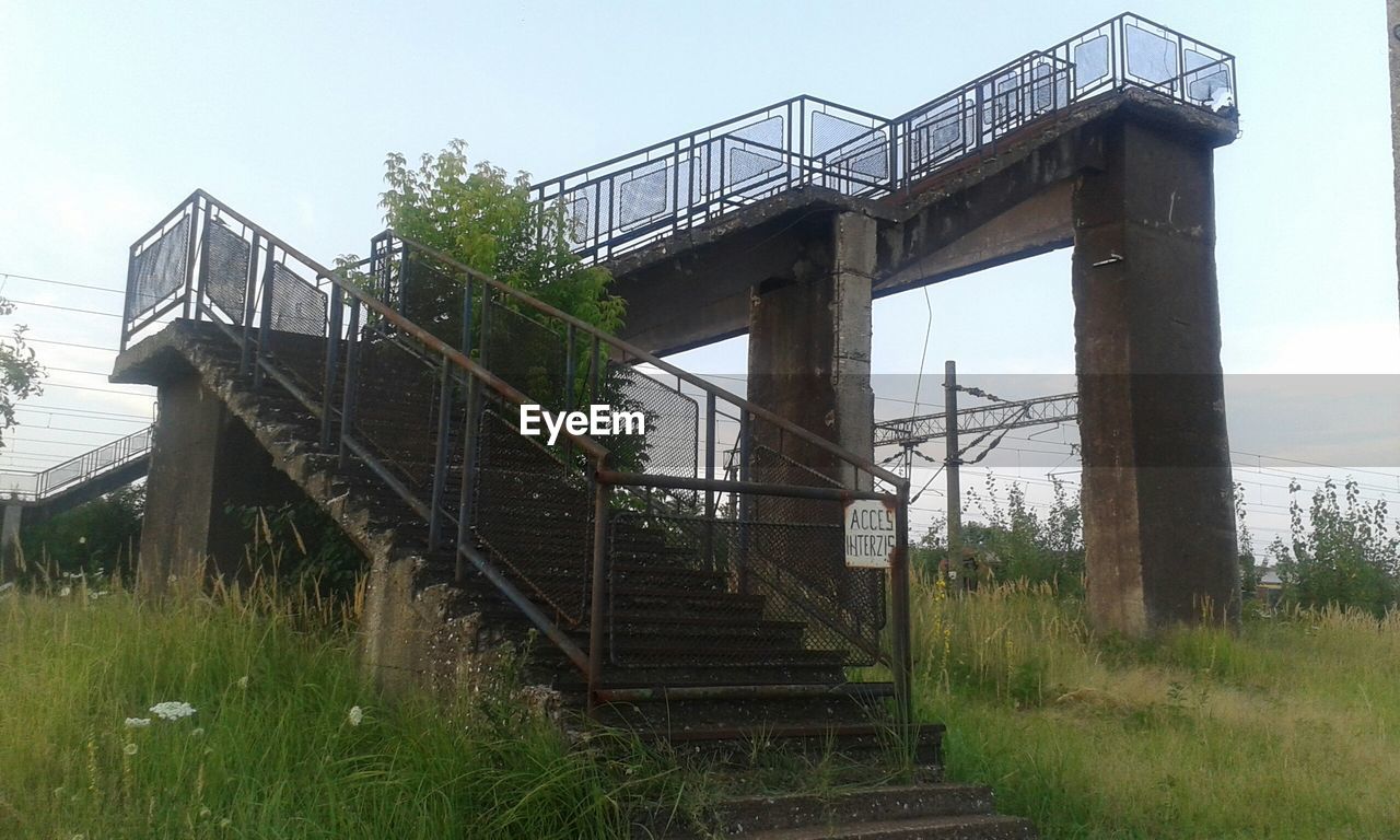 Low angle view of forbidden abandoned bridge against sky