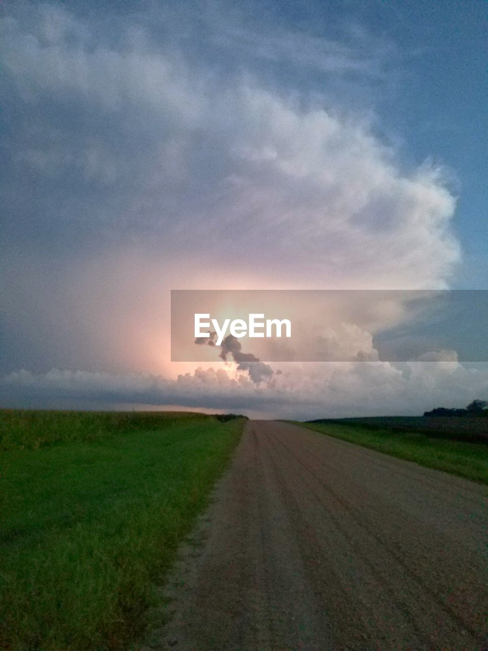 ROAD AMIDST FIELD AGAINST DRAMATIC SKY