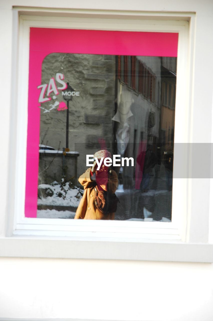 PORTRAIT OF WOMAN PHOTOGRAPHING WITH REFLECTION OF WINDOW