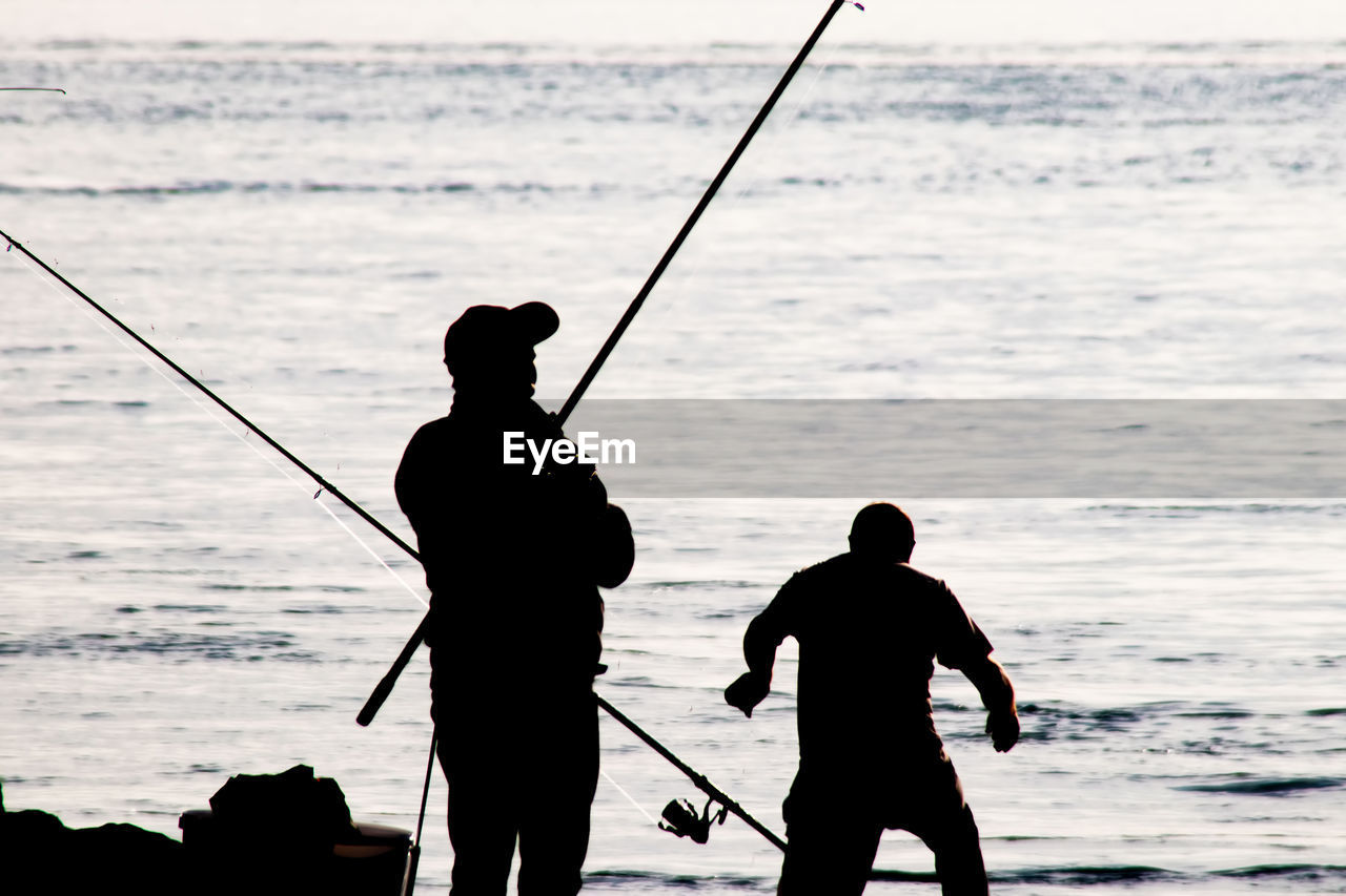 SILHOUETTE OF MAN FISHING ON BEACH