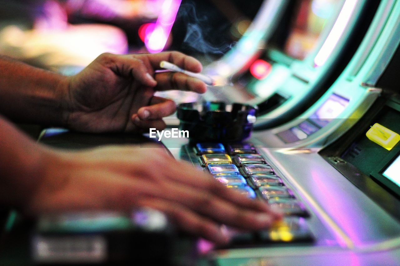 Close-up of hands playing slot machine
