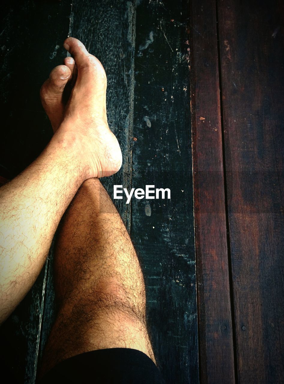 Low section of man relaxing on hardwood floor at home