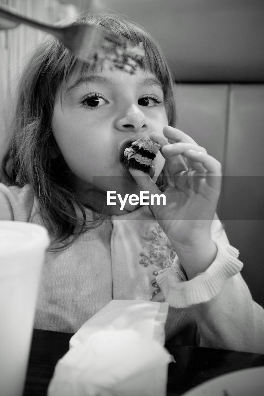 Portrait of cute girl eating cake slice at restaurant