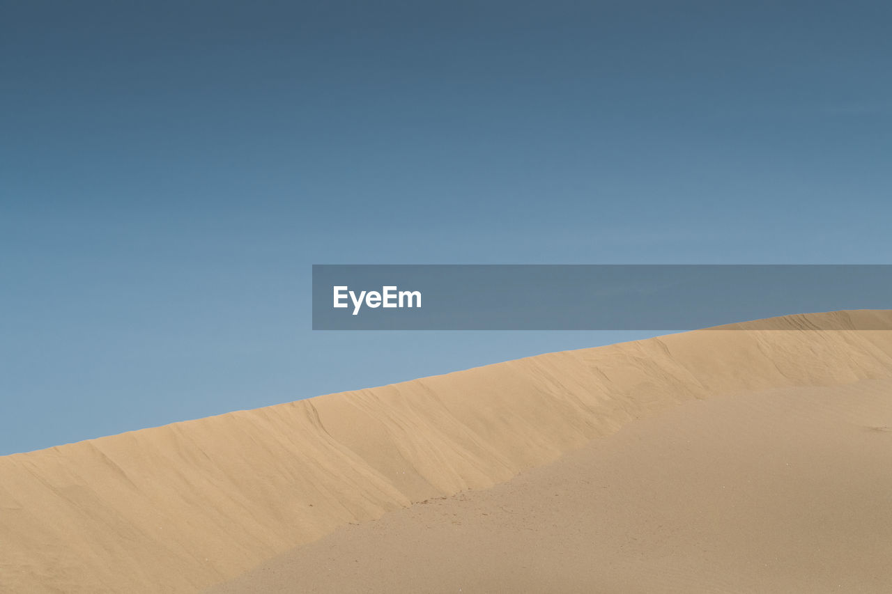 Scenic view of desert against clear blue sky