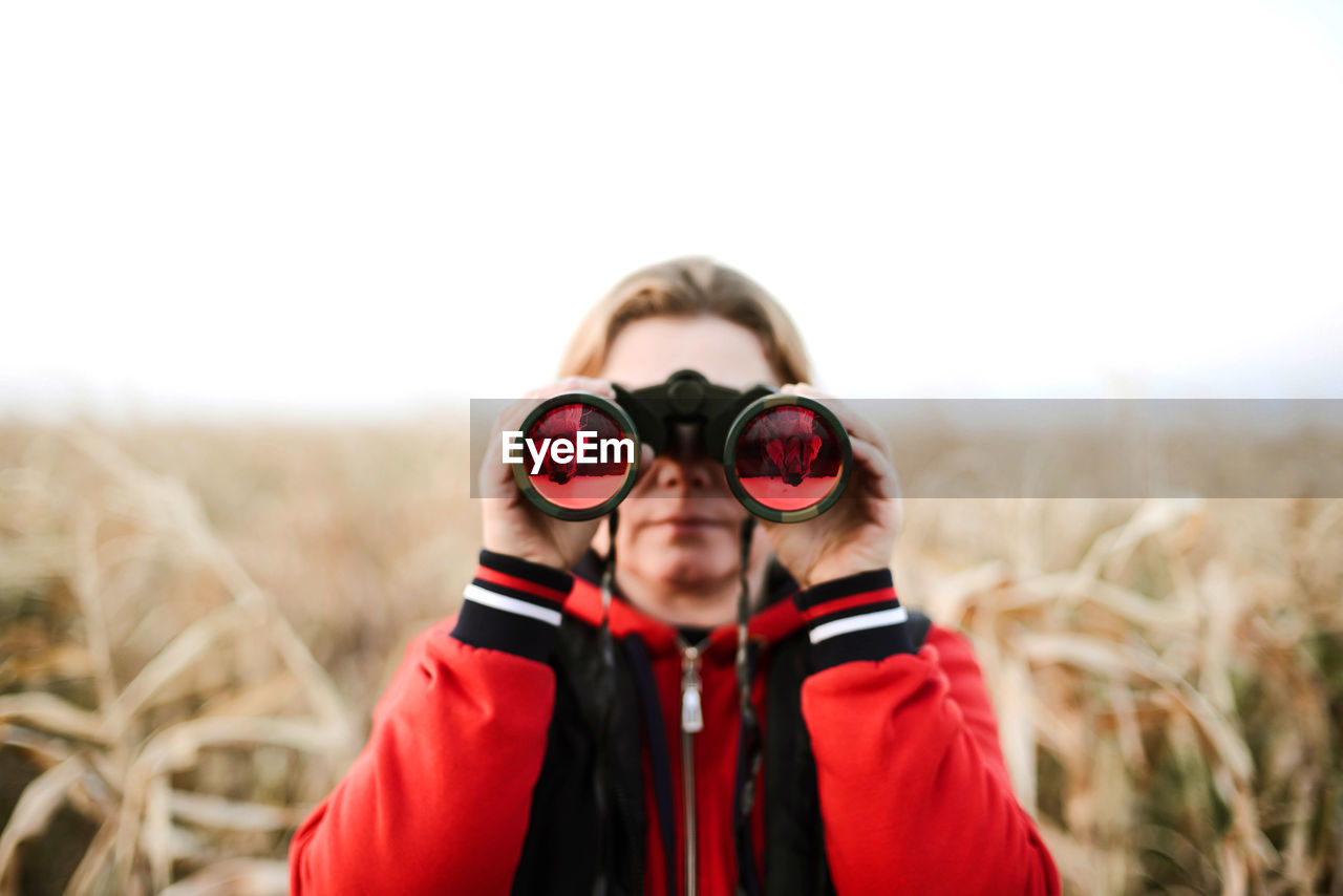 Woman holding binoculars at farm