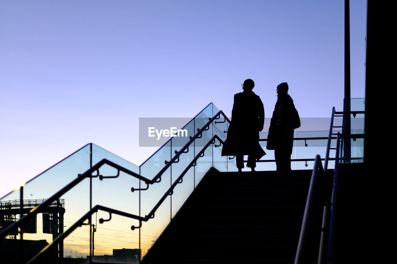 SILHOUETTE PEOPLE WALKING ON STAIRCASE AGAINST CLEAR SKY