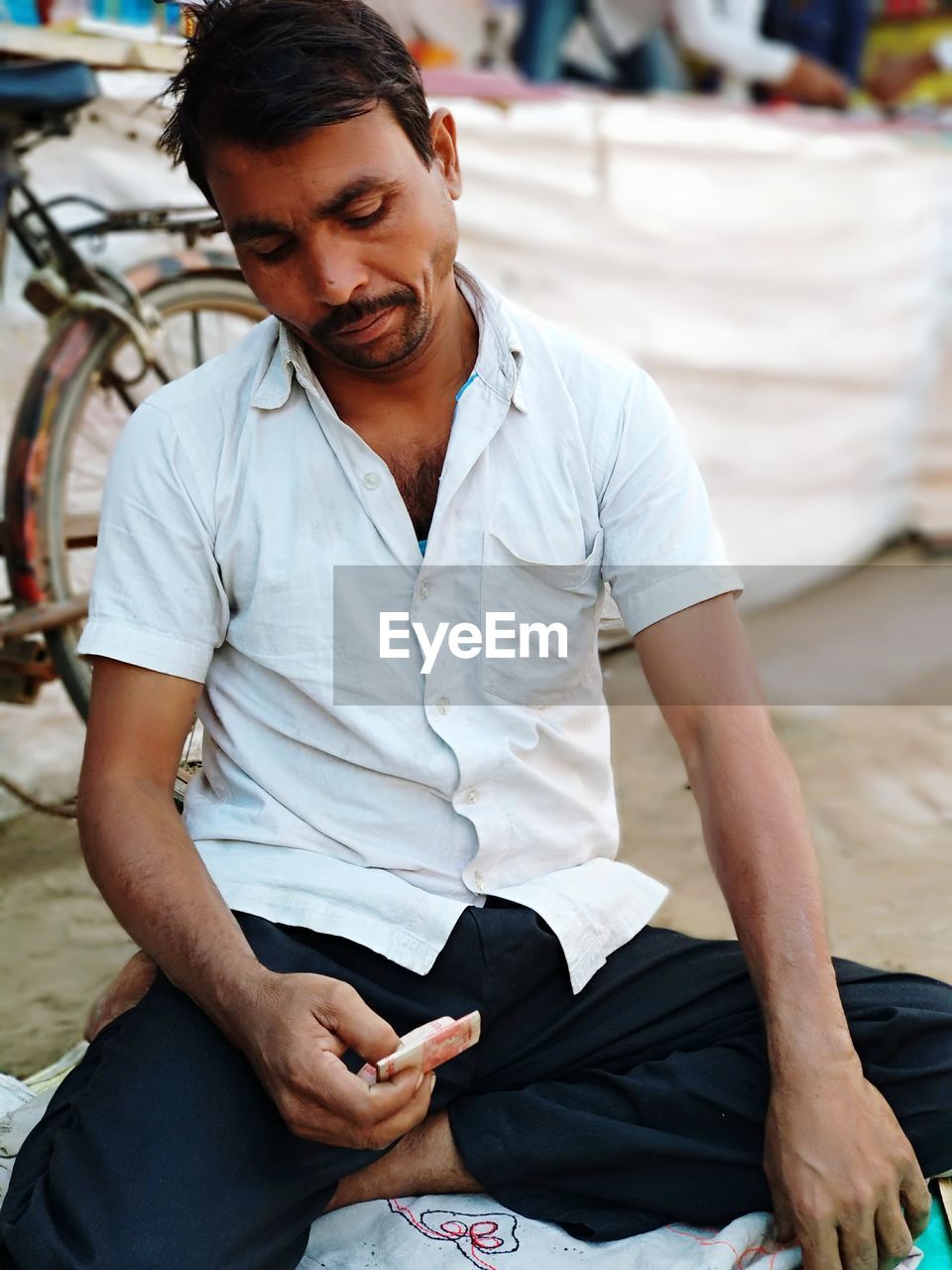 Close-up of man with paper currency sitting on road