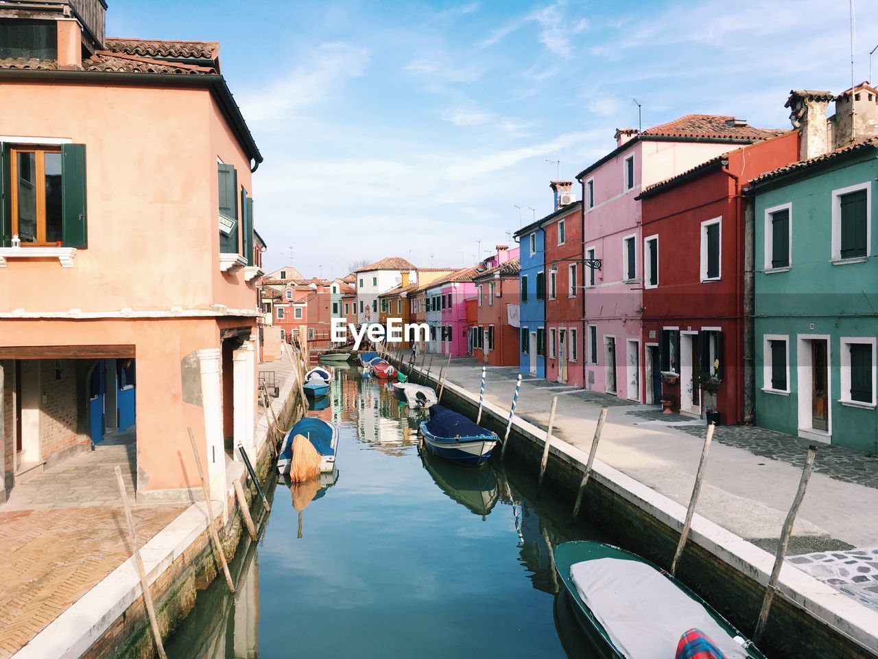 Boats moored in canal by colorful buildings