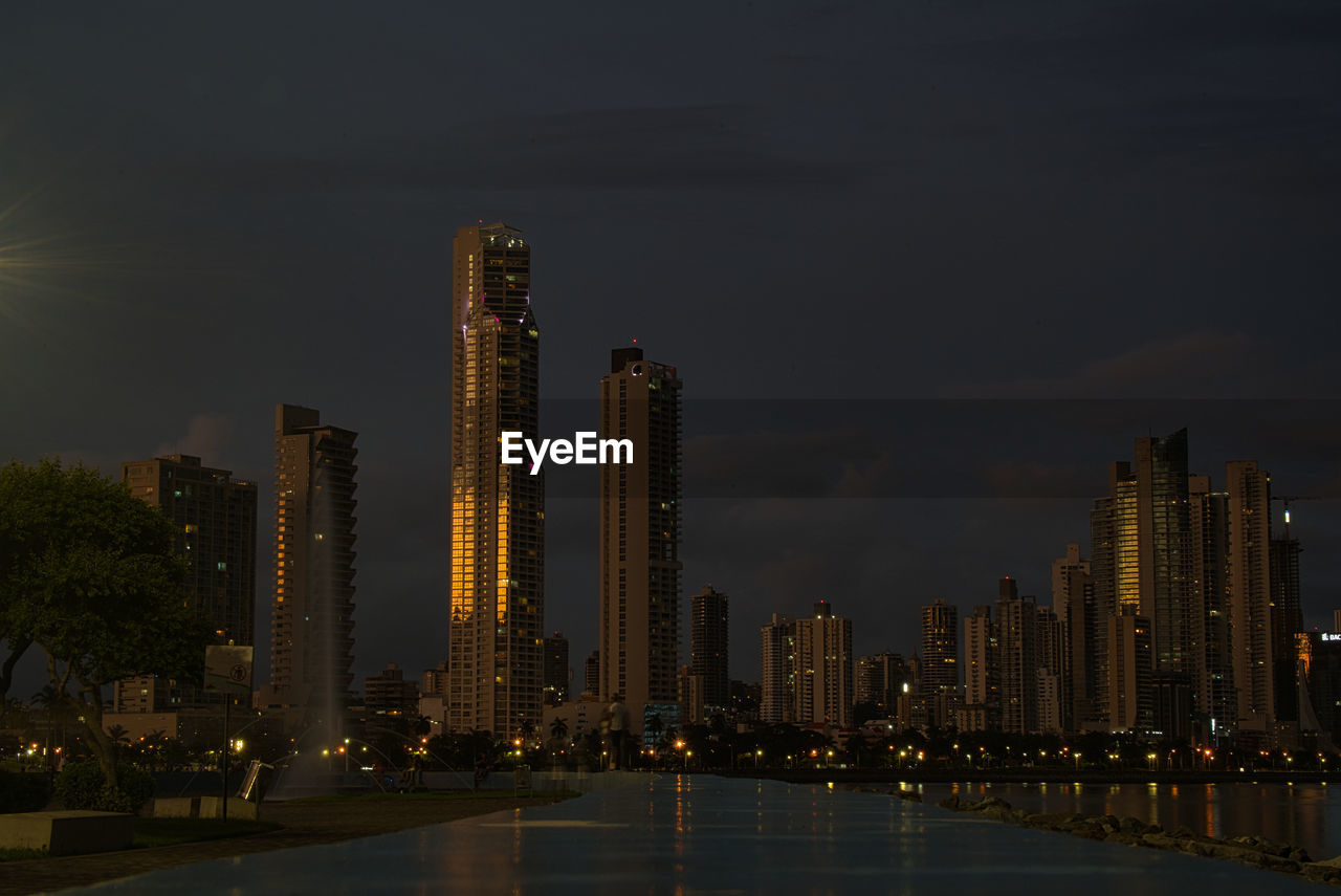 ILLUMINATED MODERN BUILDINGS AGAINST SKY AT NIGHT