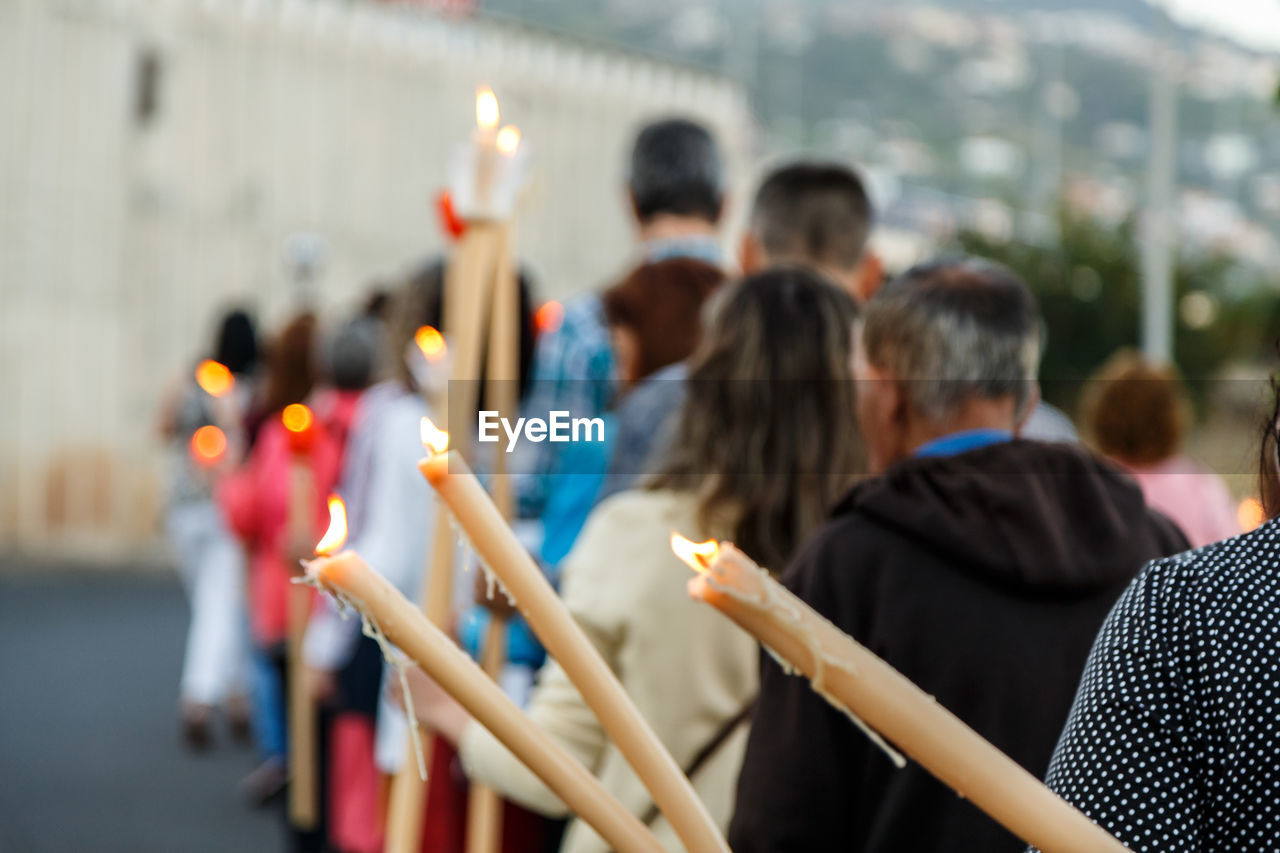 Back view of people in procession with candles in hand