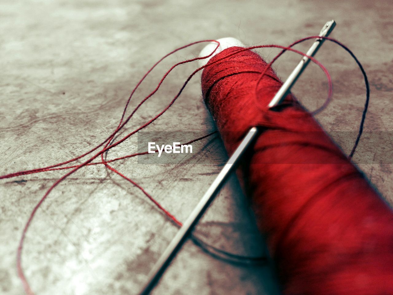 Close-up of red thread with needle fallen on floor